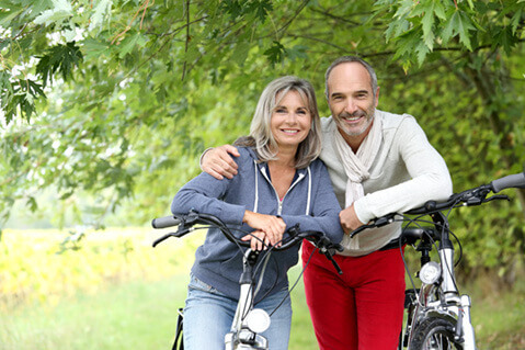 Middle aged couple biking in woods